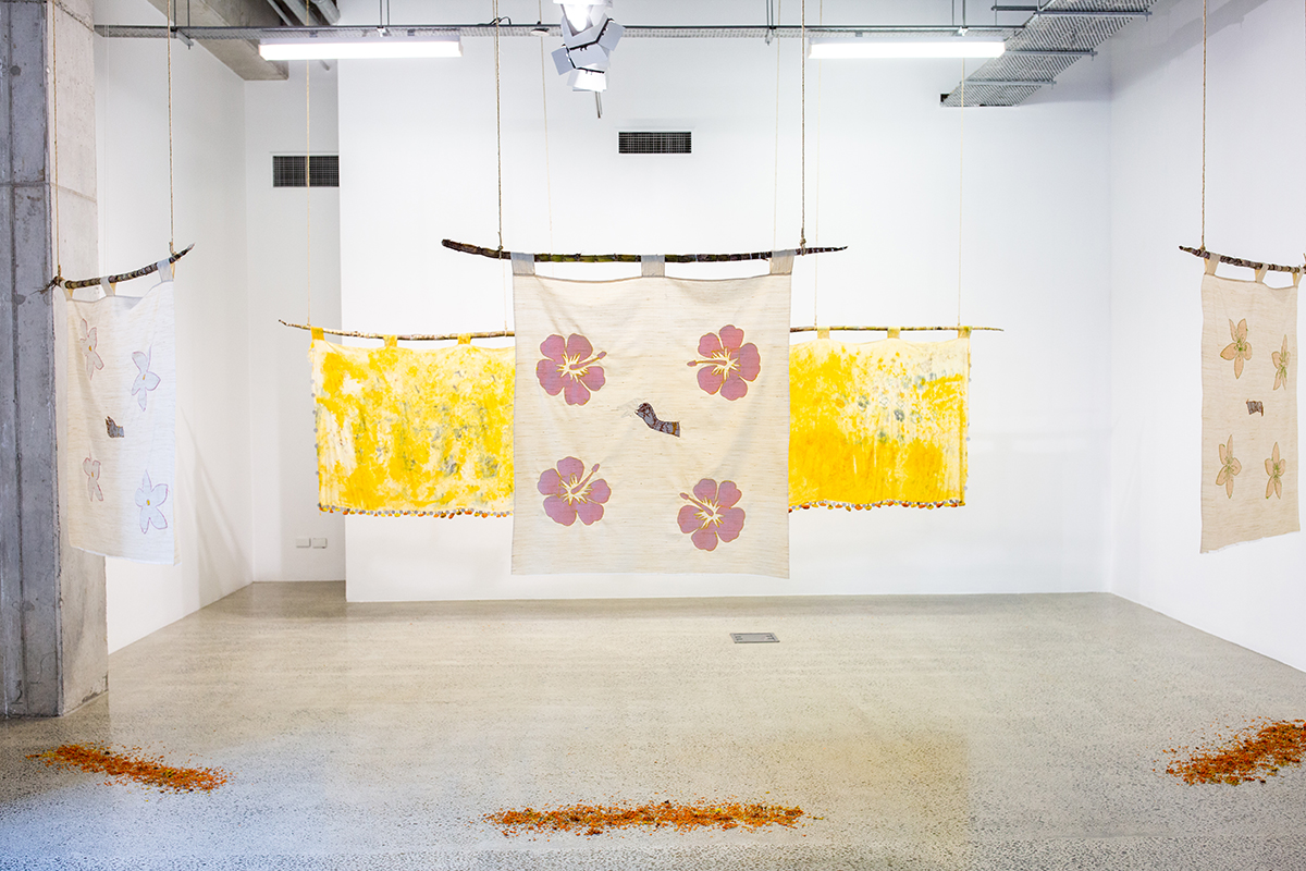 Installation of embroidered fabrics hanging from sugarcane, suspended from ceiling
