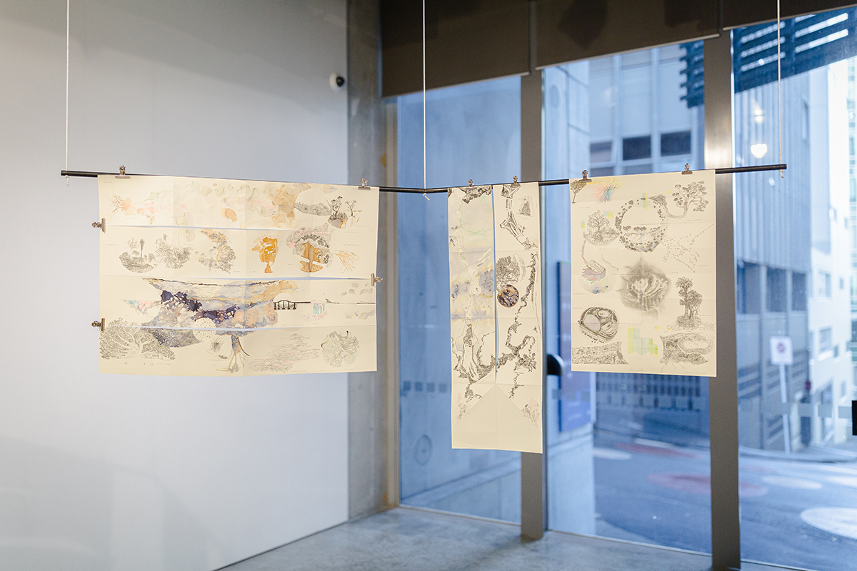 Three drawings hung from metal rod